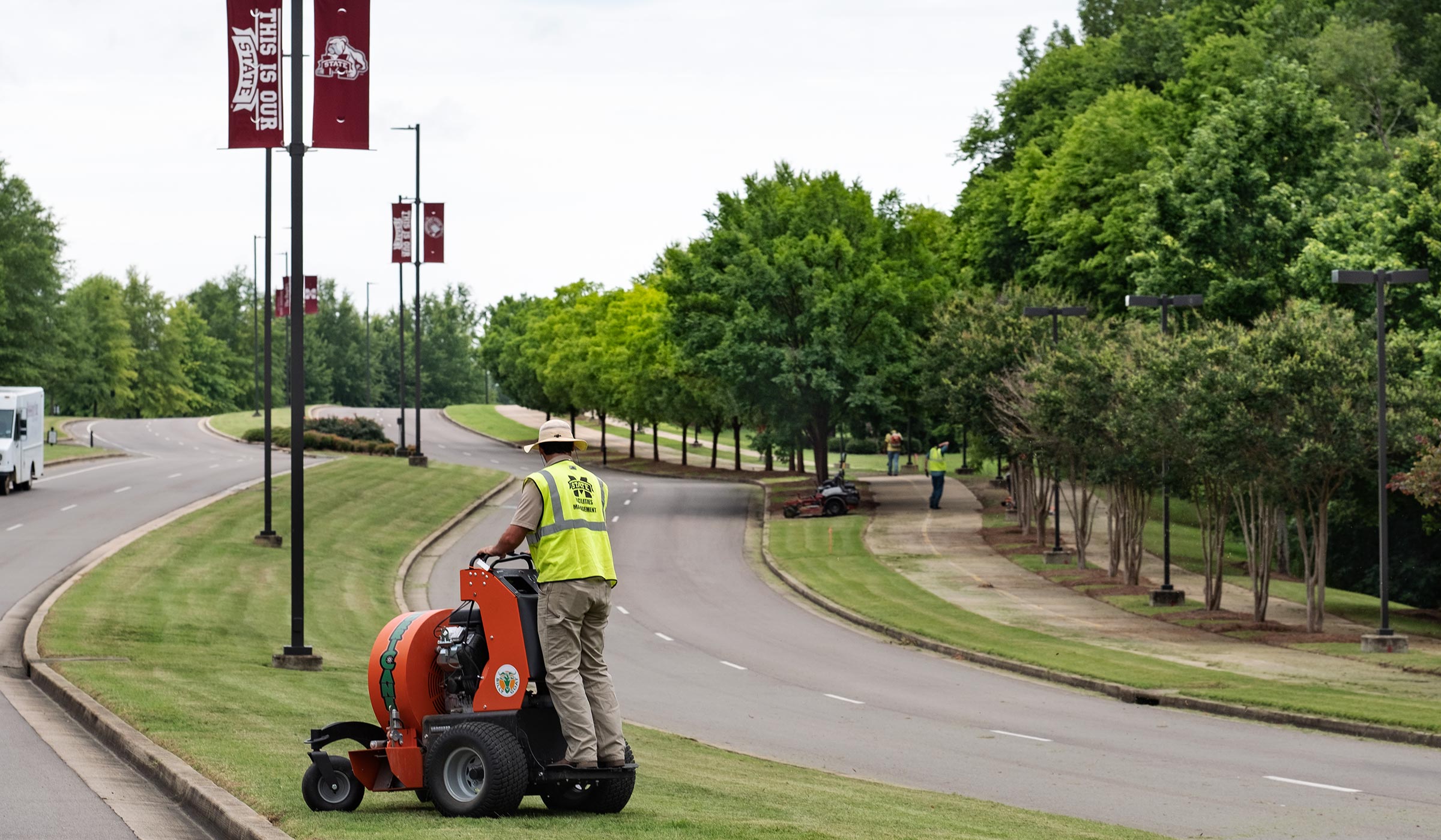 With a worker tending to the grass in the cneter median, MSU's landscape crew works to maintain MSU's North Entrance Drive..