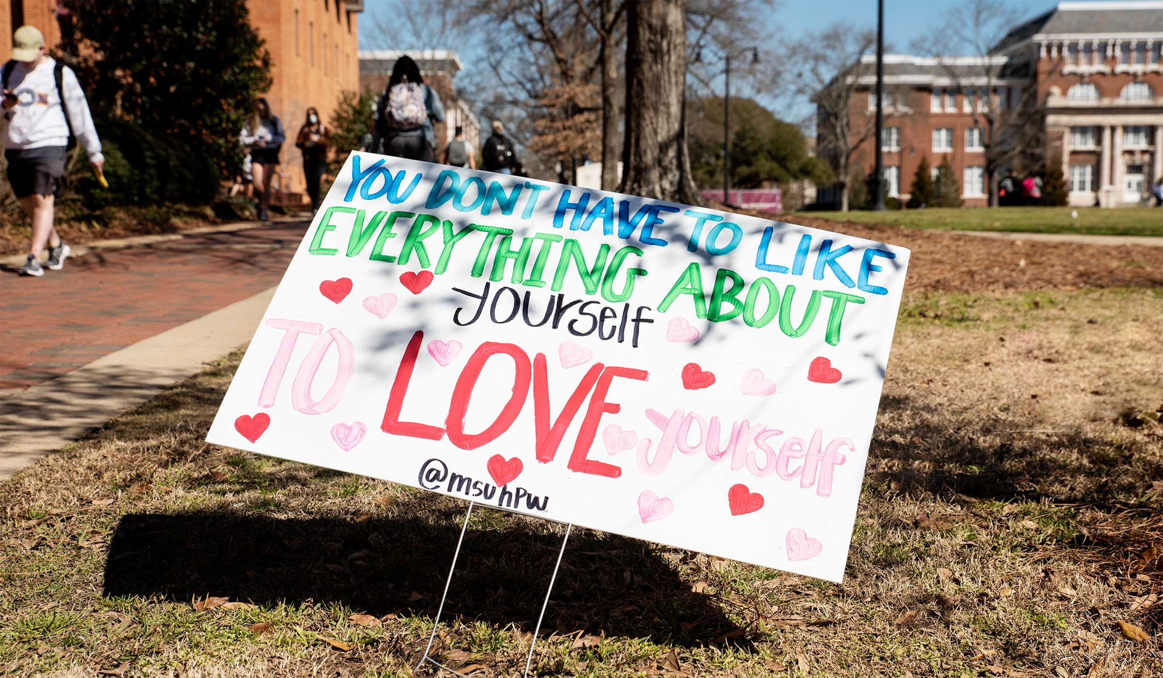 A sign on the Drill Field reminds passerbys "You Don't Have to Like Everything About Yourself to Love Yourself."