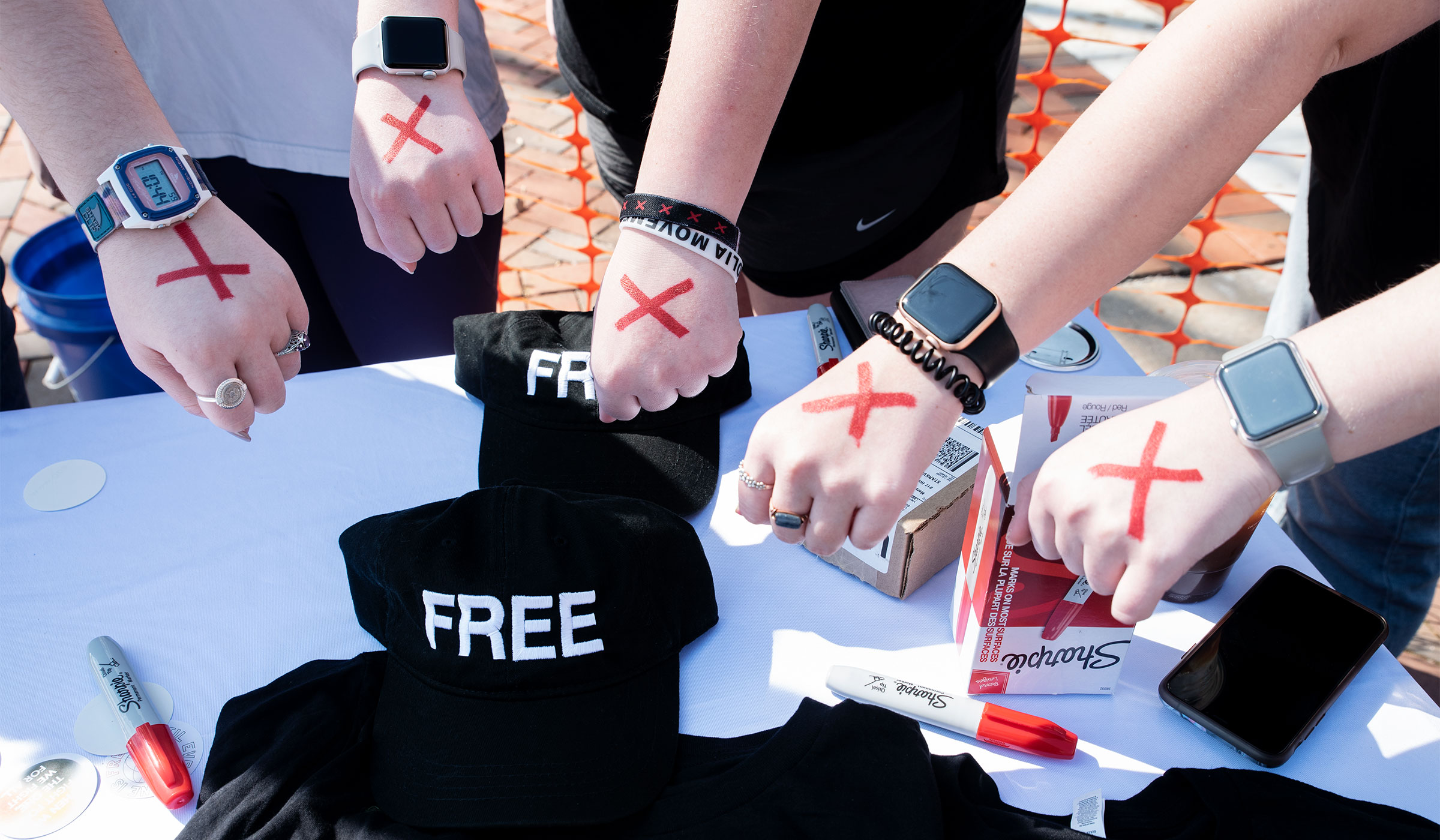 An array of hands with red "X" marks on them, displayed by members of the "No Longer Bound" student organization.