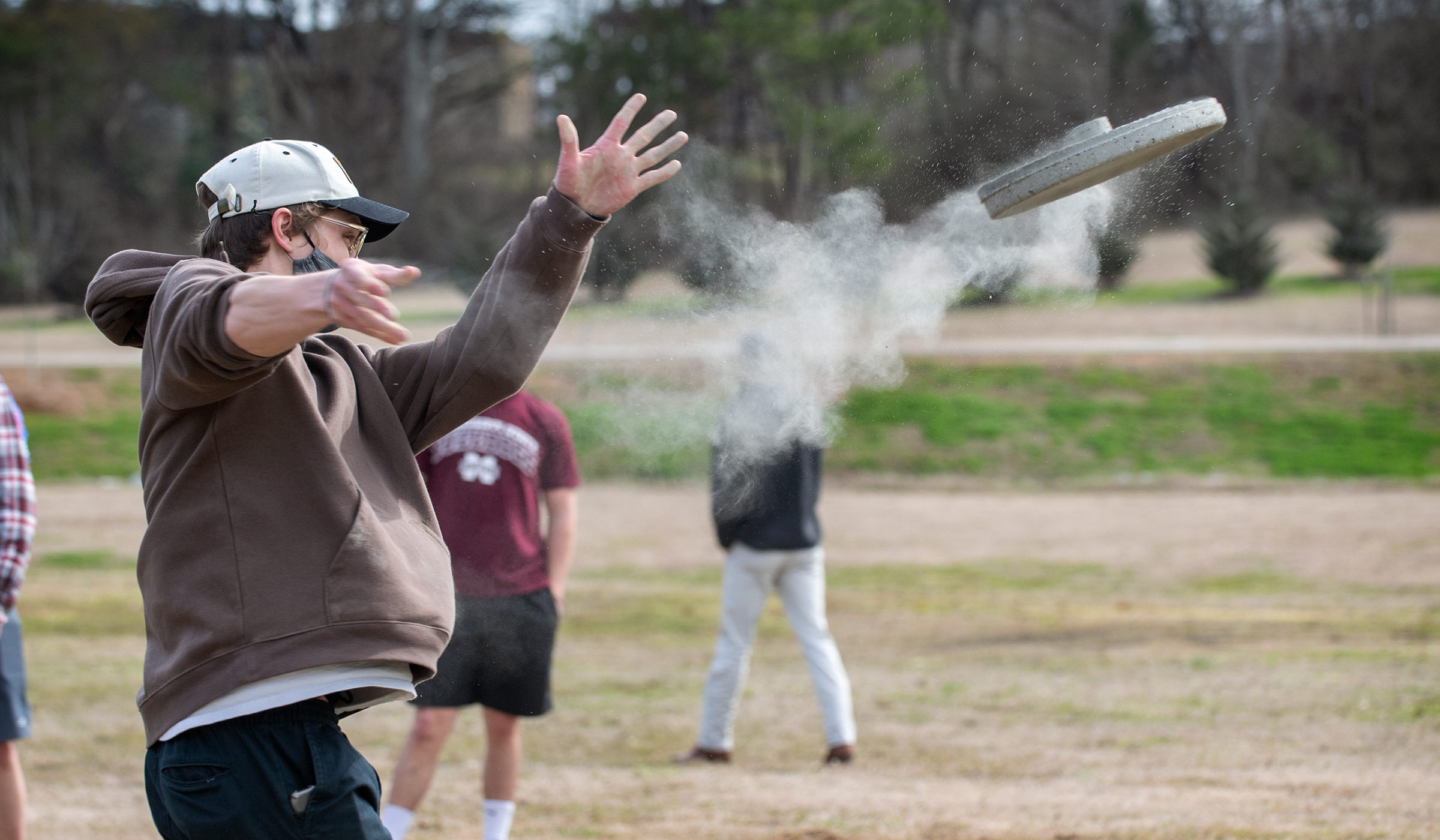 As junior architecture student Mic Wilkins throws his team's concrete frisbee, a trail of dust follows the spinning disk.