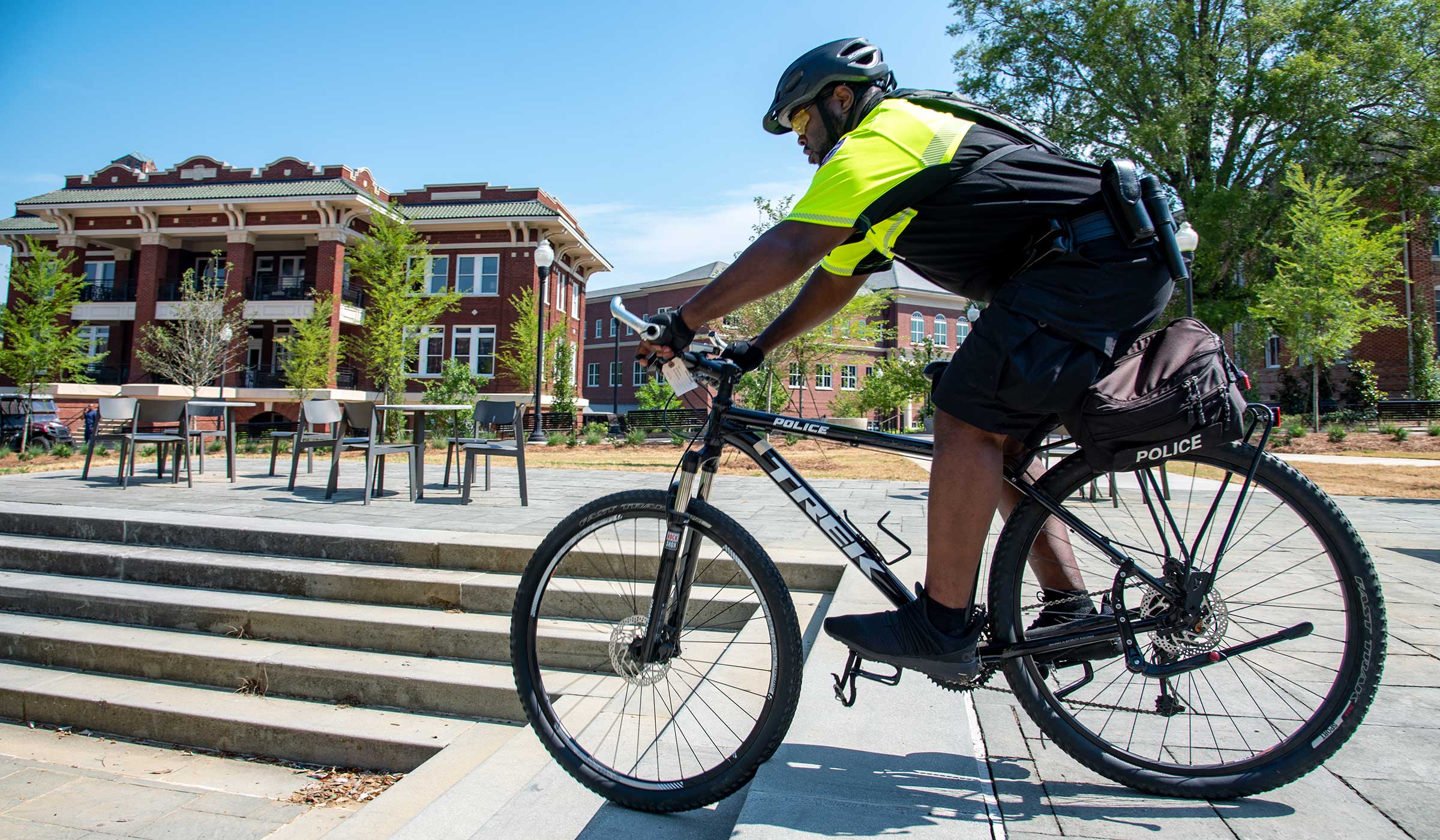 Man in neon green and black police gear navigating stairs on bicycle