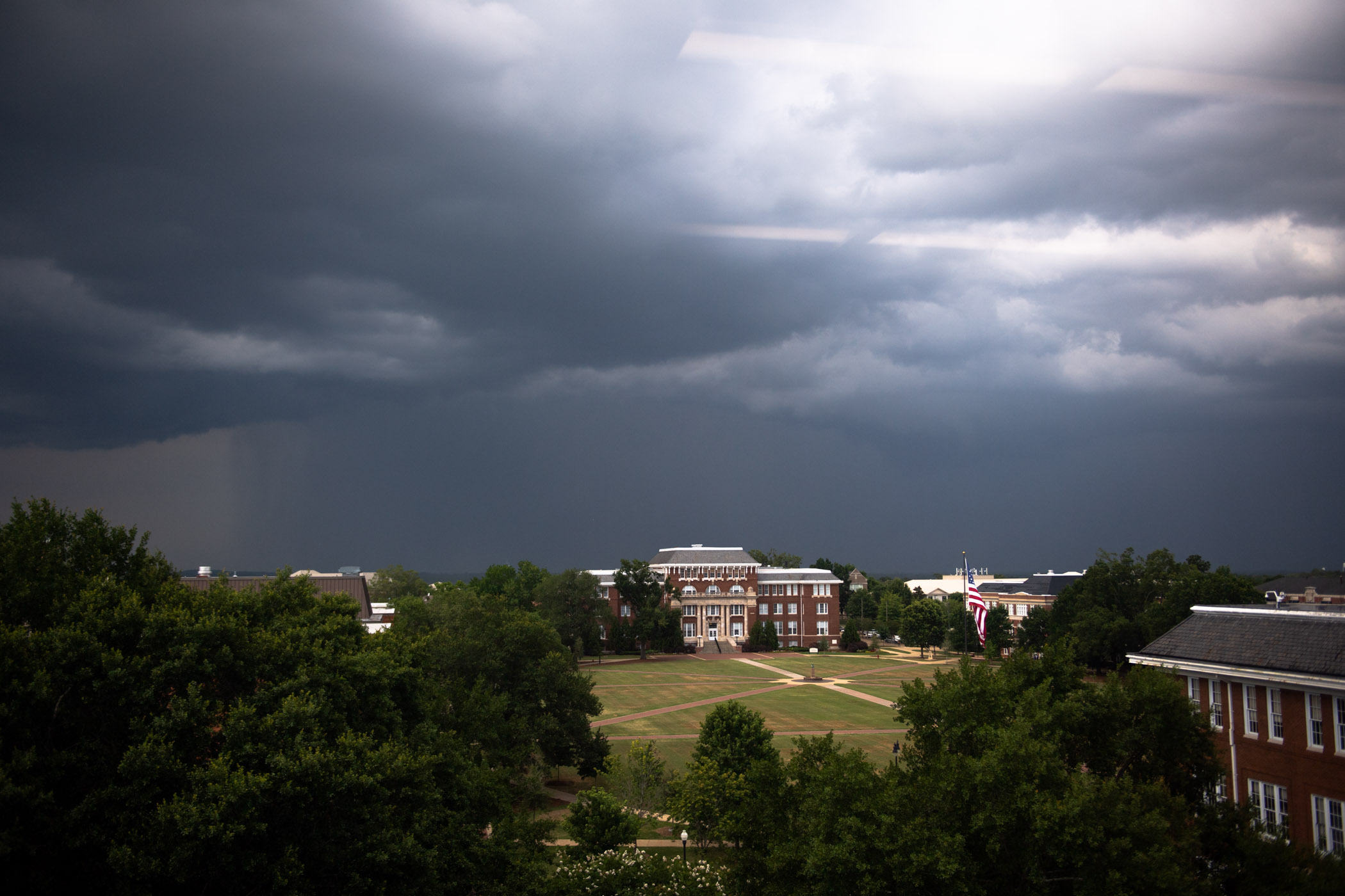 A dark grey sky cascades across MSU's Drill Field as an incoming summer shower is seen above Lee Hall