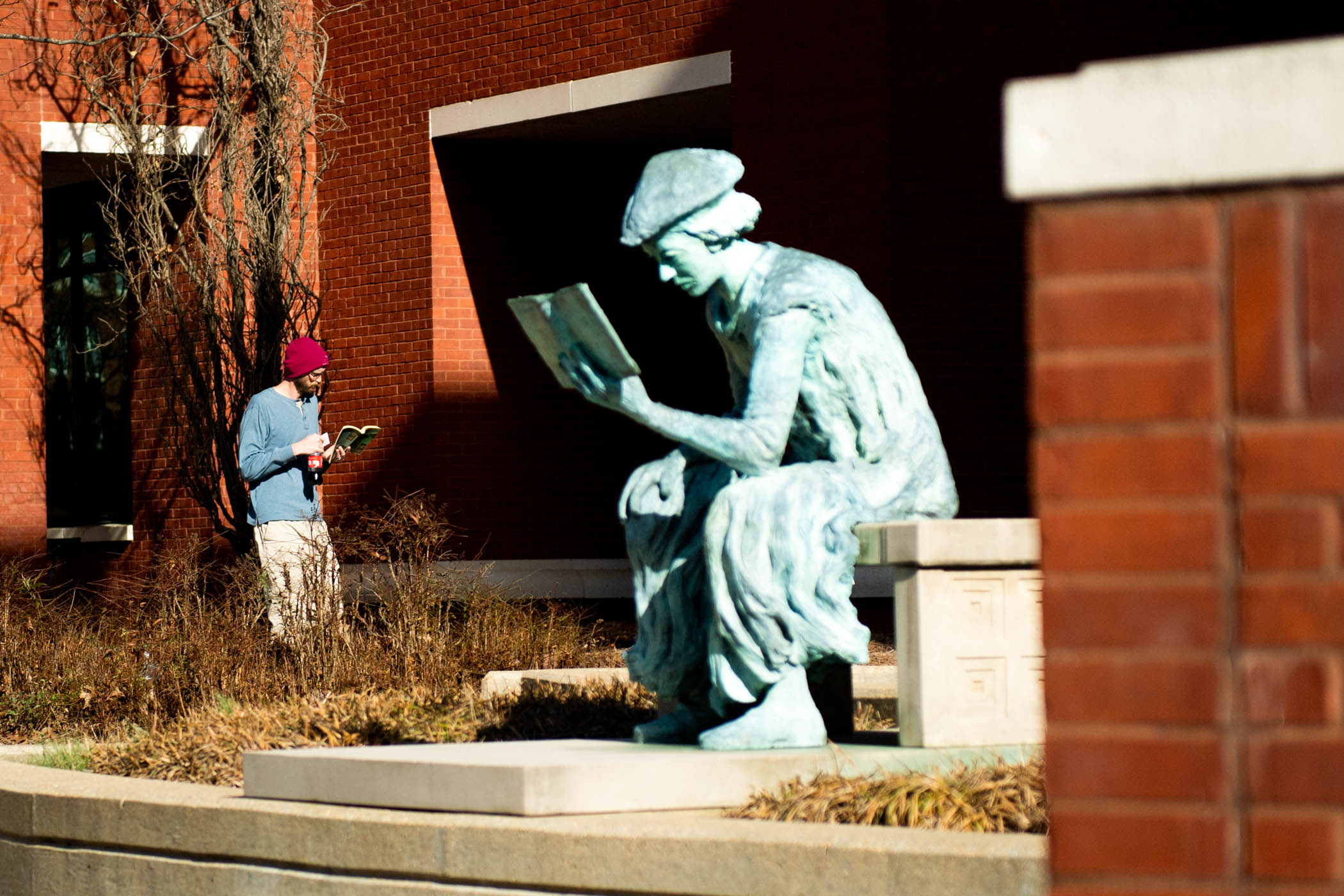 Passerby and MSU Libraries' favorite statue, "The Scholar," enjoy their books on a sunny afternoon.