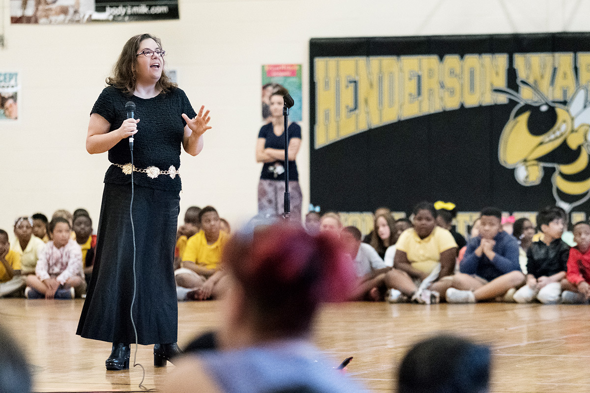 Astronomy professor Donna Pierce speaks with a microphone before assembly of students at Henderson Ward Stewart's gymnasium.
