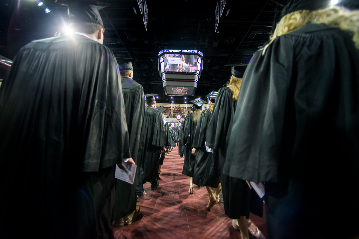 Graduates walk onto the floor of Humphrey Coliseum.