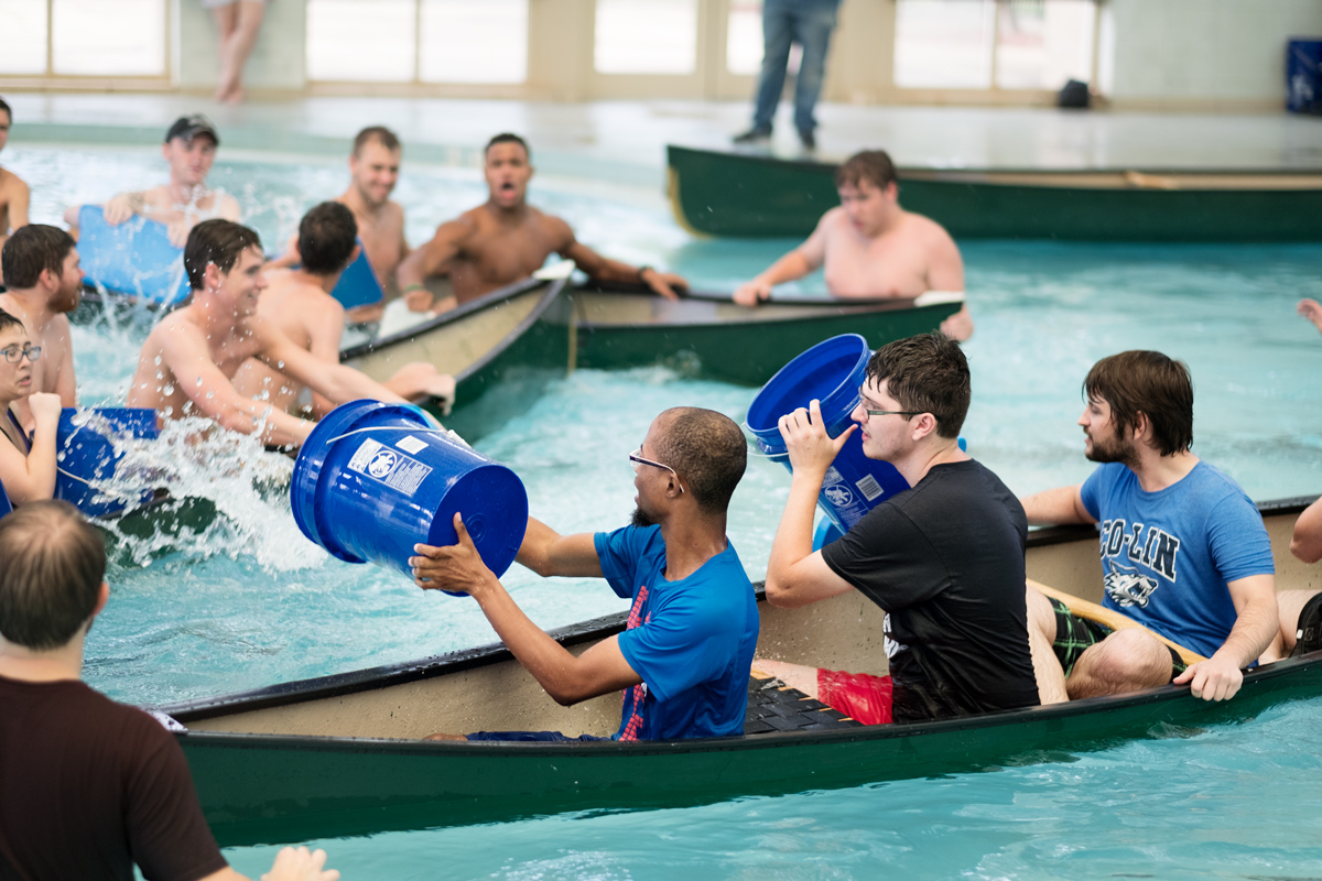 Canoes full of students throw buckets full of water at eachother in an attempt to sink each other's boats.